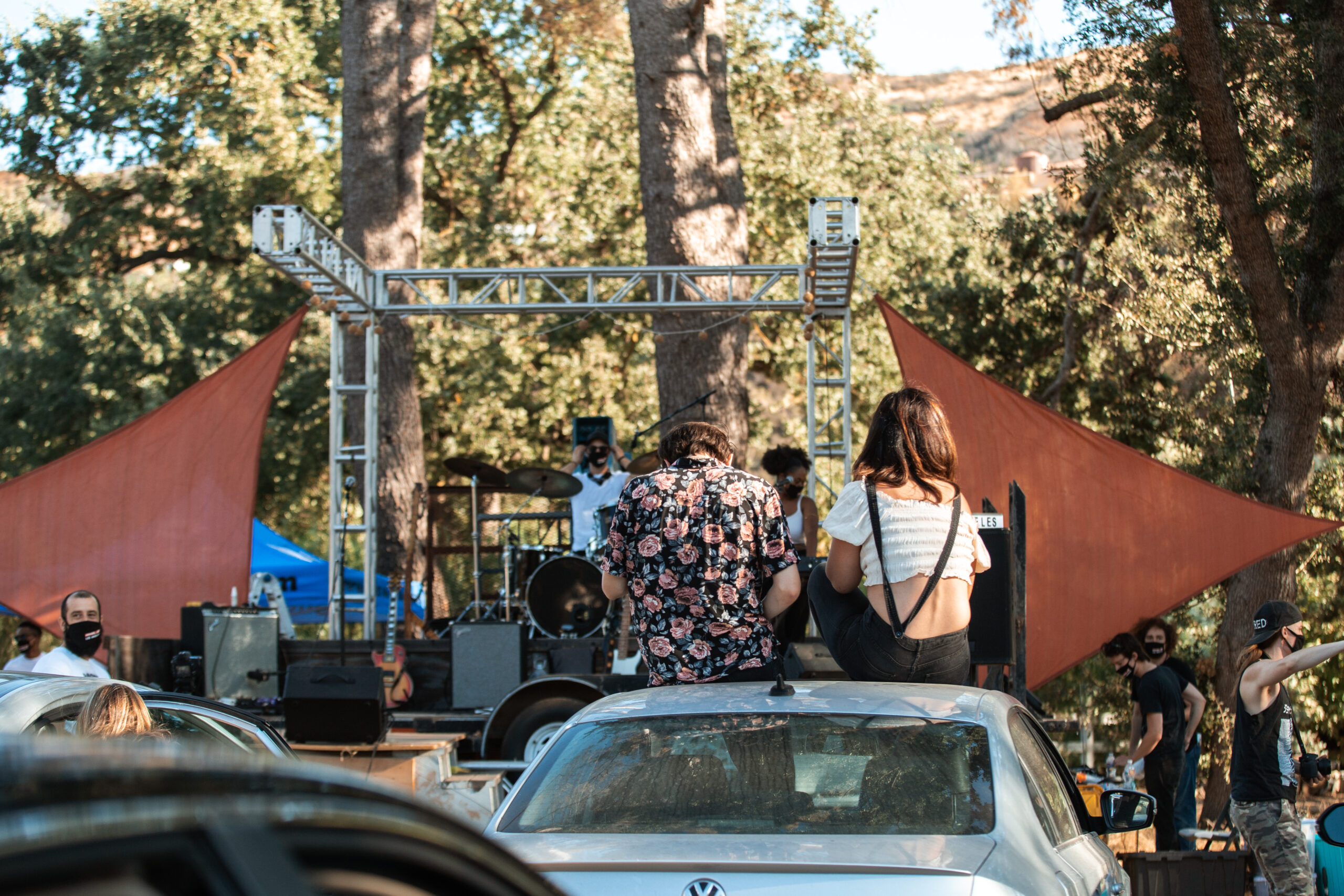 concert attendees on the roofs of their car look on
